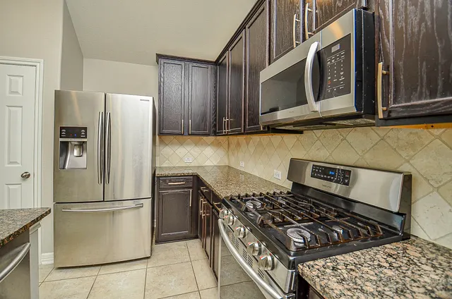 a kitchen with stainless steel appliances granite countertop a stove a refrigerator and a cabinets