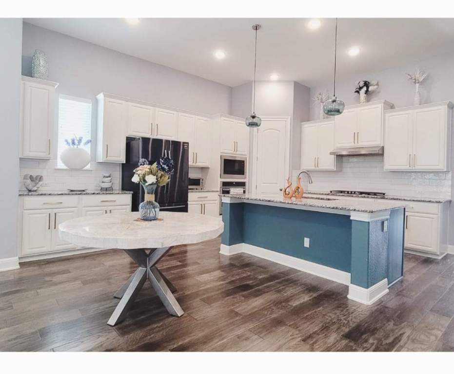 1800 Ficuzza Way Leander, TX 78641 - Photo 2 of 8 Kitchen with tasteful backsplash, white cabinetry, appliances with stainless steel finishes, decorative light fixtures, and a center island with sink