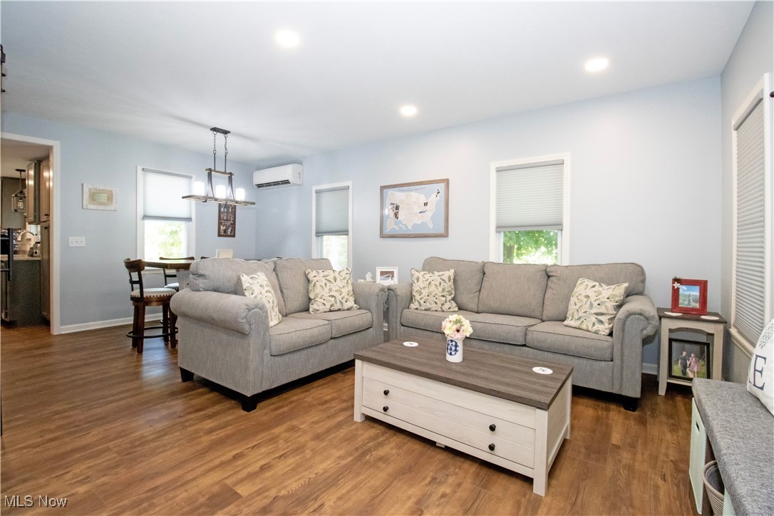 8984 Spencer Road Homerville, OH 44235 - Photo 14 of 27 Living room with plenty of natural light, dark wood-type flooring, a wall mounted AC, and a chandelier