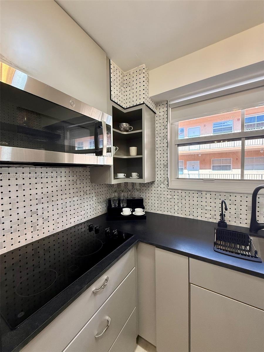 199 Southwest 12th Avenue, Unit 404A Miami, FL 33130 - Photo 19 of 65 a kitchen with a sink a microwave a stove and cabinets