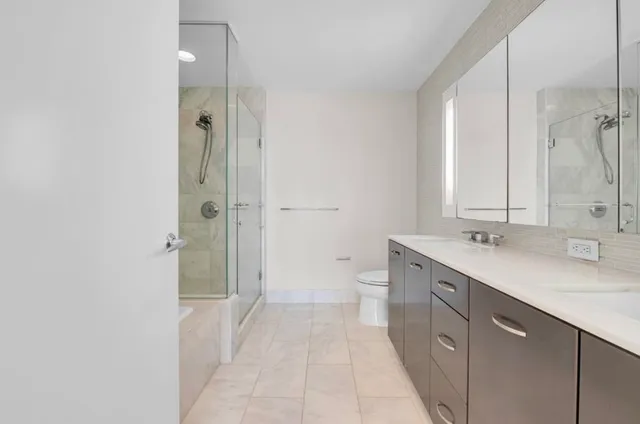 a bathroom with a double vanity sink toilet mirror and windows