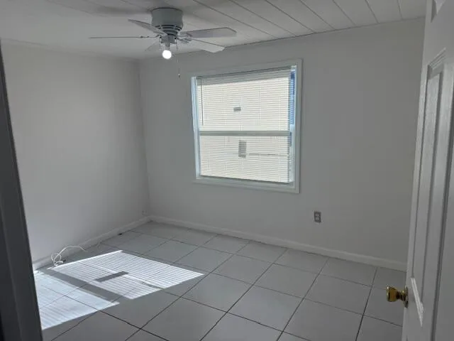 an empty room with chandelier fan and windows