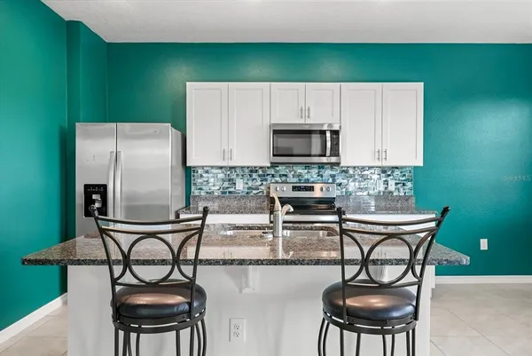 a kitchen with stainless steel appliances a table chairs and a refrigerator