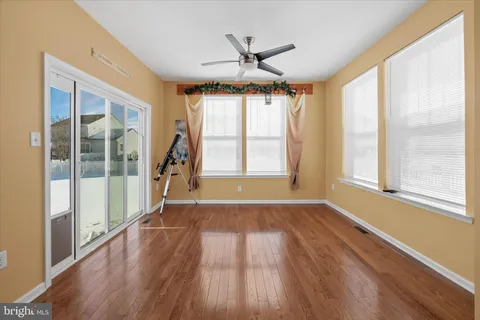 a view of empty room with wooden floor and fan