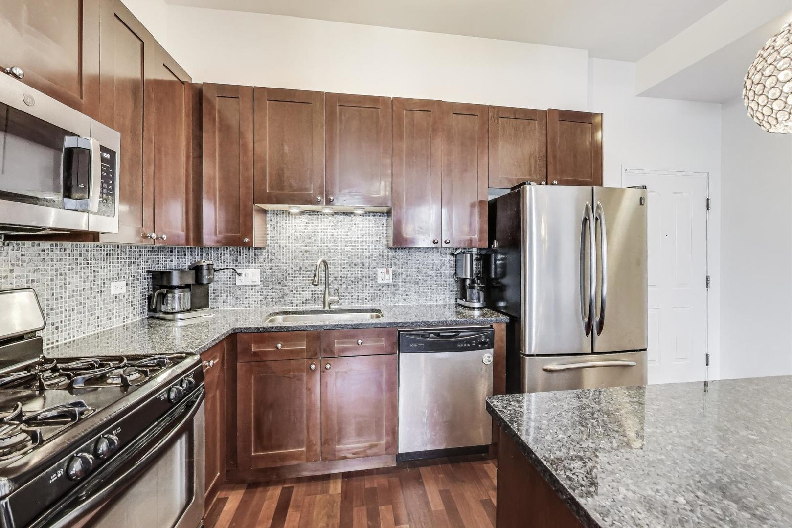 1464 South Michigan Avenue, Unit 1609 Chicago, IL 60605 - Photo 17 of 45 a kitchen with wooden cabinets and stainless steel appliances