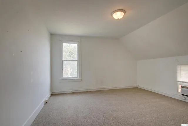 an empty room with a window and chandelier fan