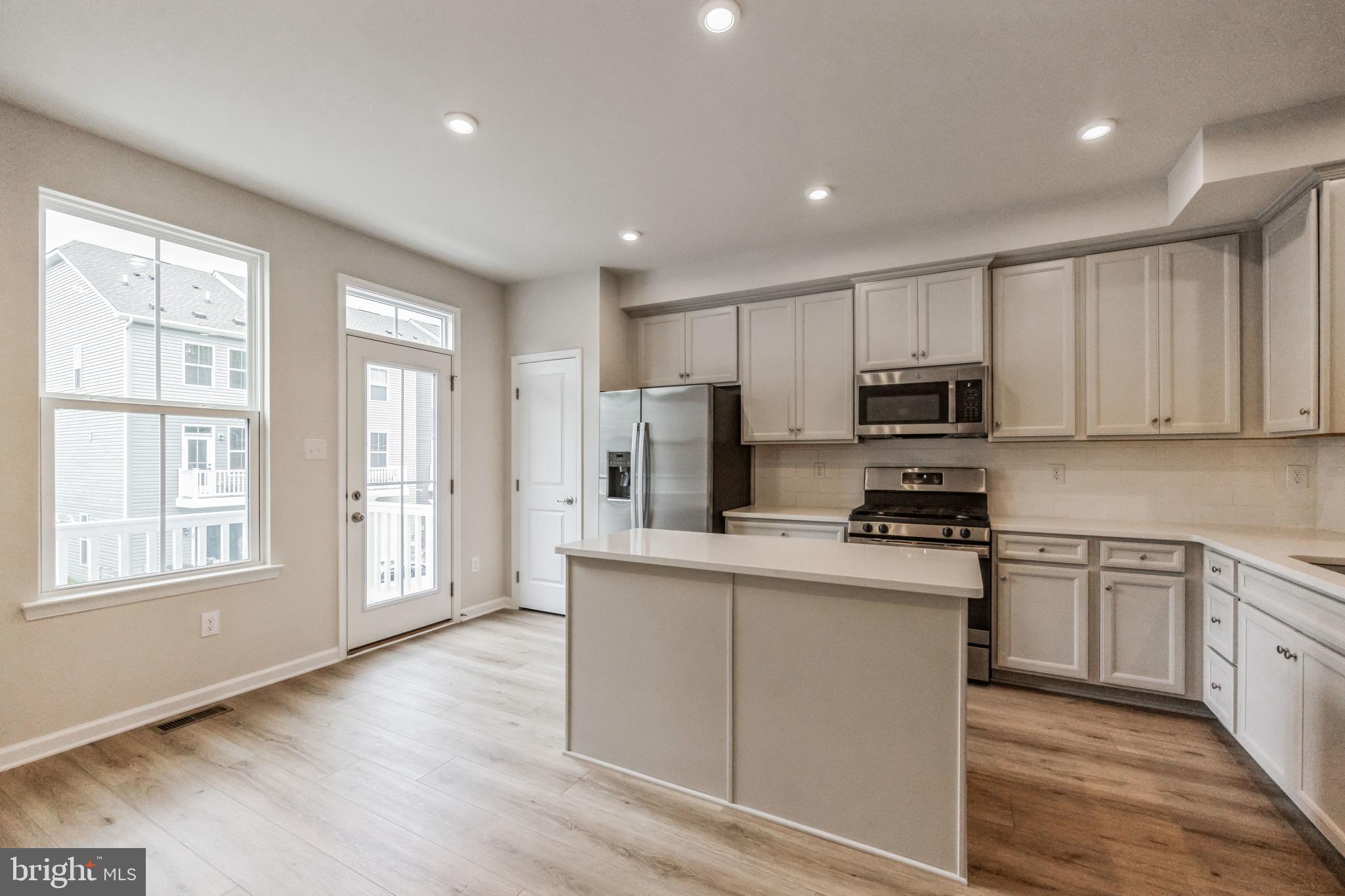 28 Sidney Lane Stratford, NJ 08084 - Photo 11 of 30 a kitchen with stainless steel appliances granite countertop a stove a sink dishwasher a refrigerator and white cabinets with wooden floor