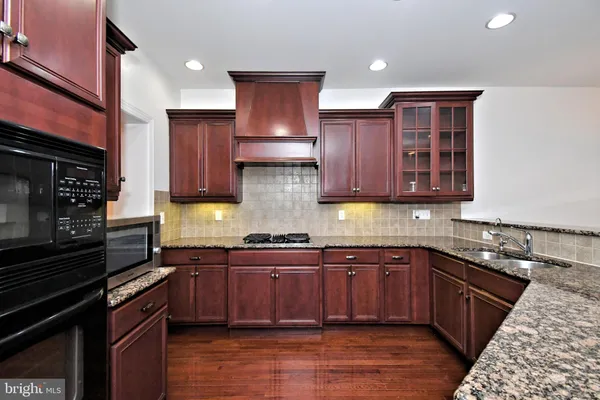 a kitchen with stainless steel appliances granite countertop wooden cabinets stove top oven and sink