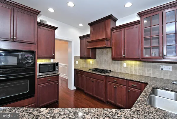 a kitchen with stainless steel appliances granite countertop a stove a sink dishwasher and a microwave oven with large cabinets