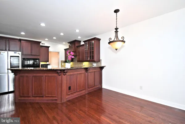 a kitchen with stainless steel appliances granite countertop a refrigerator a sink dishwasher a stove and a wooden floor