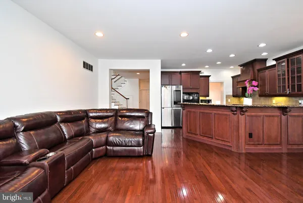 a living room with stainless steel appliances furniture and wooden floors