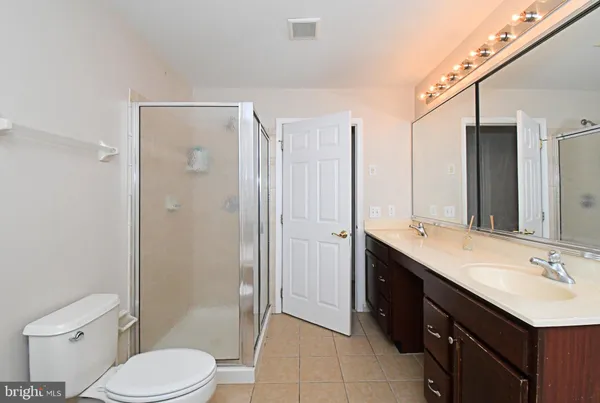 a bathroom with a double vanity sink toilet mirror and shower