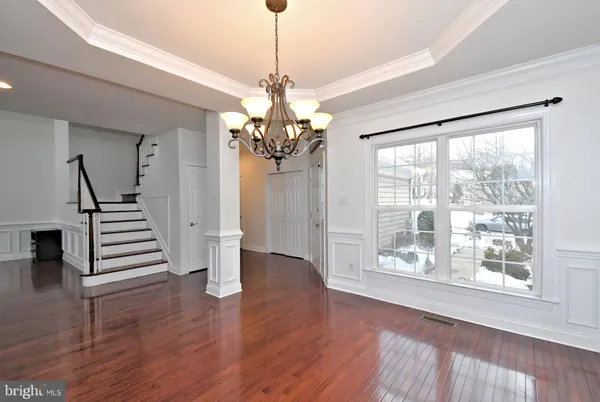 a view of a room with wooden floor staircase and a chandelier