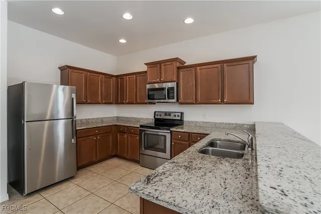 a kitchen with granite countertop a refrigerator and a stove top oven