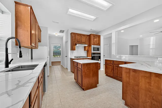 a large kitchen with stainless steel appliances granite countertop a sink and a stove