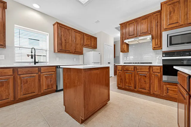 a kitchen with stainless steel appliances granite countertop a stove a sink dishwasher and a microwave oven with cabinets