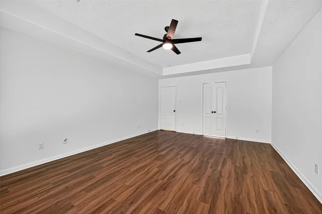 a view of empty room with wooden floor and ceiling fan