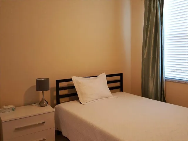 a bedroom with a bed and chair with a window