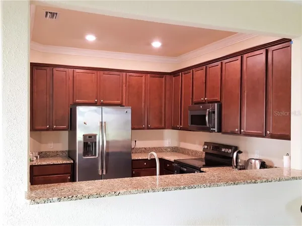 a kitchen with stainless steel appliances granite countertop a refrigerator a stove and a sink with wooden cabinets