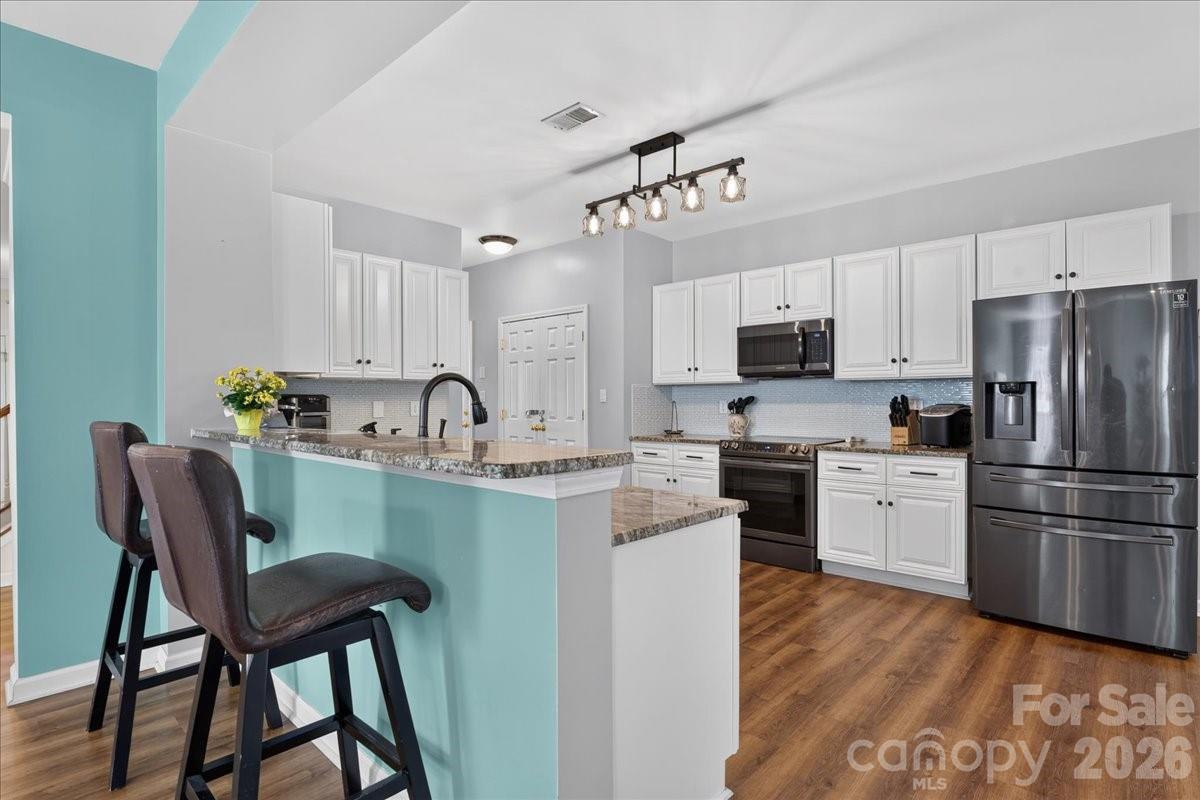 8006 Fine Robe Drive Indian Trail, NC 28079 - Photo 17 of 36 a kitchen with stainless steel appliances granite countertop a table chairs microwave and sink