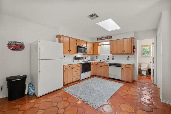 a kitchen with granite countertop a refrigerator a sink dishwasher a stove top oven a refrigerator and cabinets