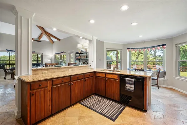 a large kitchen with stainless steel appliances granite countertop a sink and wooden cabinets