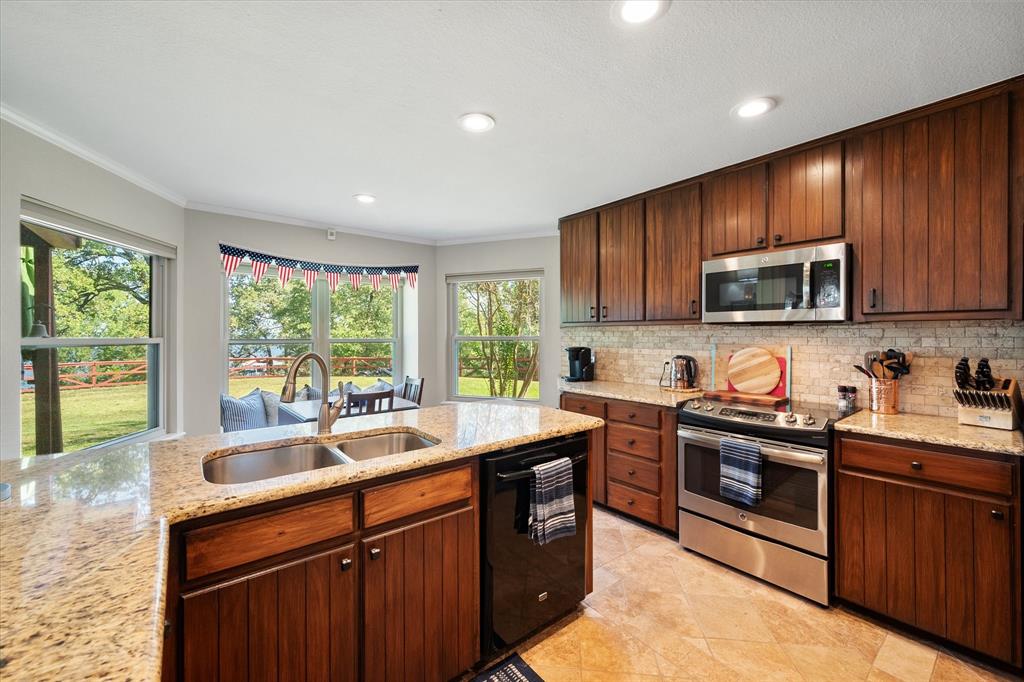 195 Highview Streetman, TX 75859 - Photo 7 of 40 a kitchen with stainless steel appliances granite countertop wooden cabinets a sink dishwasher a stove and a refrigerator with wooden floor