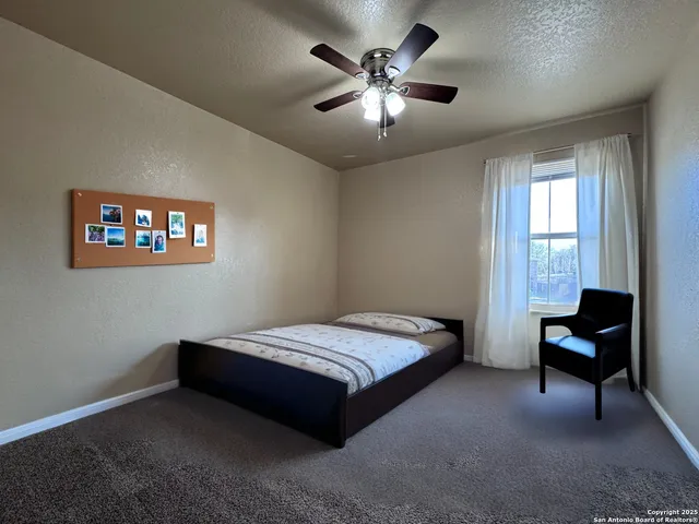 an empty room with chandelier fan and windows