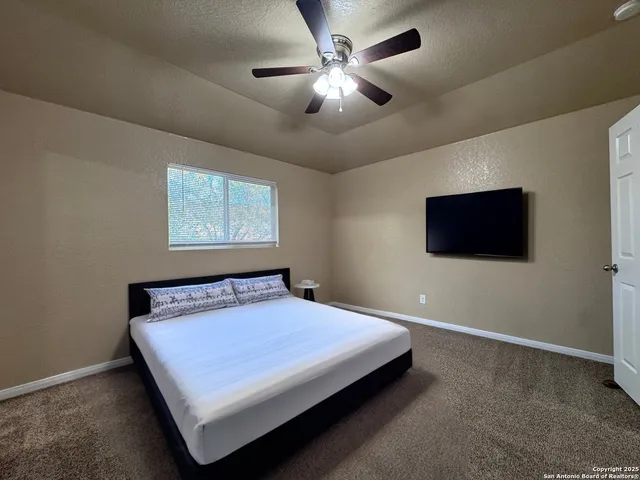 an empty room with a chandelier fan and windows