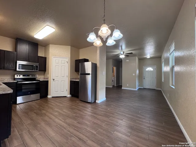 a kitchen with stainless steel appliances granite countertop a refrigerator a stove and a wooden floors