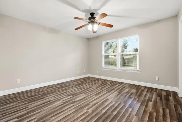a view of an empty room with wooden floor and a window