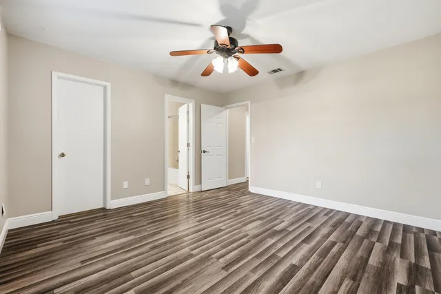 an empty room with wooden floor and windows