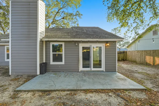 a view of a wooden house with a large tree and wooden fence