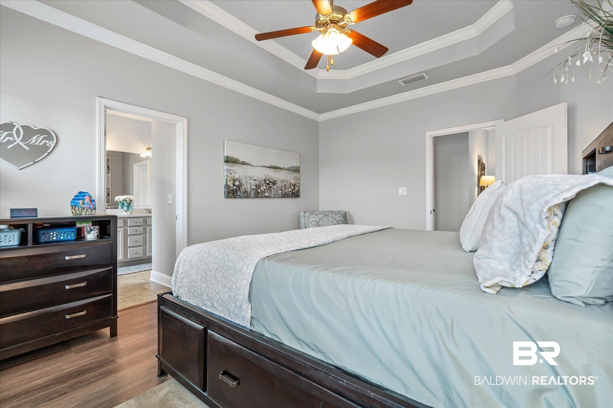 10677 Orkney Way Spanish Fort, AL 36527 - Photo 10 of 22 Bedroom featuring a raised ceiling, wood finished floors, crown molding, ceiling fan, and ensuite bathroom