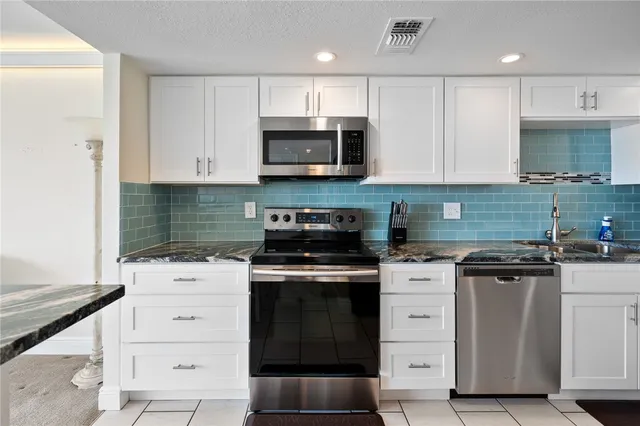 a kitchen with granite countertop white cabinets and stainless steel appliances