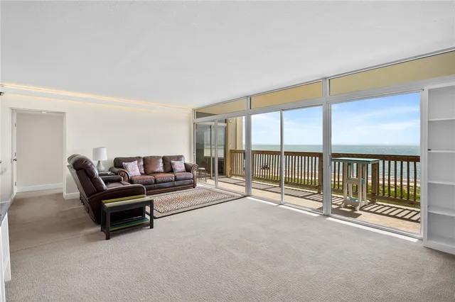 a living room with a large window and a ceiling fan