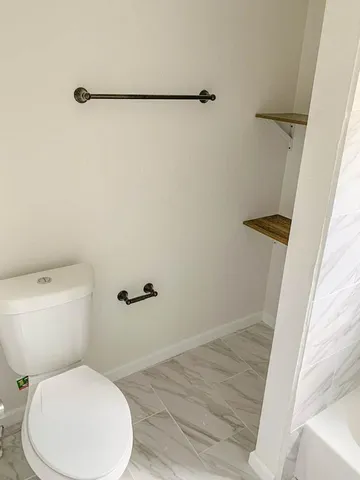a white toilet sitting next to a shower