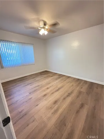 a view of an empty room with wooden floor and chandelier