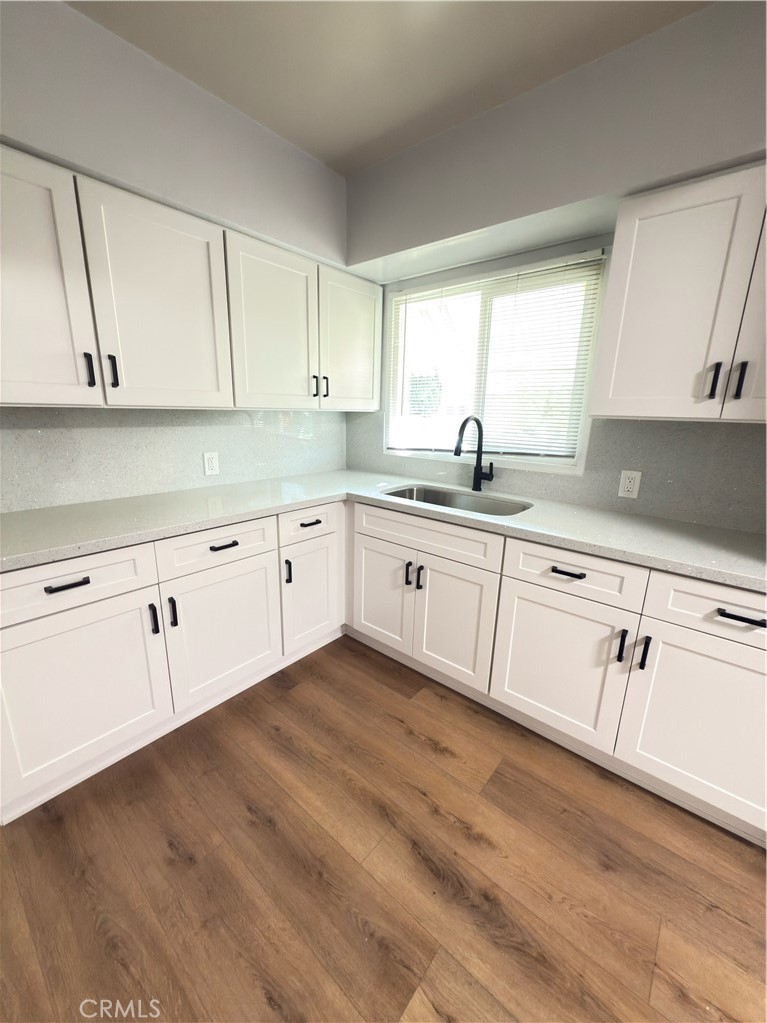 7457 Mt Vernon Street Riverside, CA 92504 - Photo 4 of 16 a kitchen with white cabinets sink and dishwasher with wooden floor