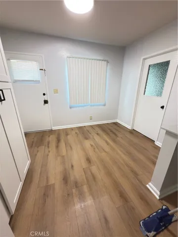 a view of an empty room with wooden floor and a window