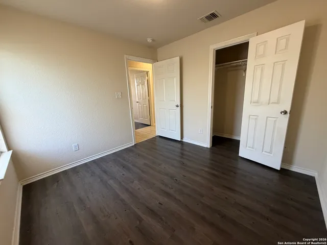 a view of an empty room with wooden floor and closet
