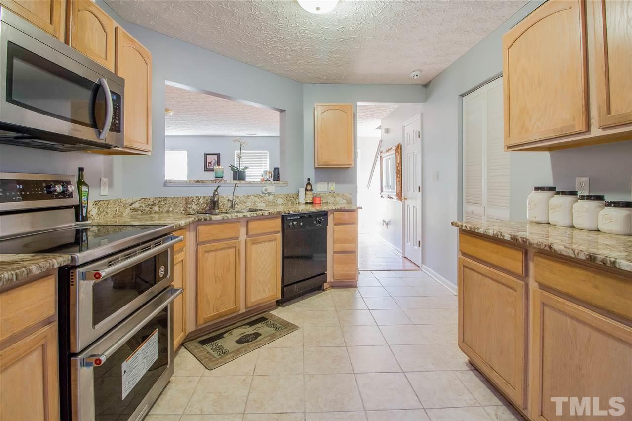 5729 Forest Point Road Raleigh, NC 27610 - Photo 11 of 26 a kitchen with stainless steel appliances granite countertop a stove top oven a sink dishwasher a refrigerator and cabinets with wooden floor