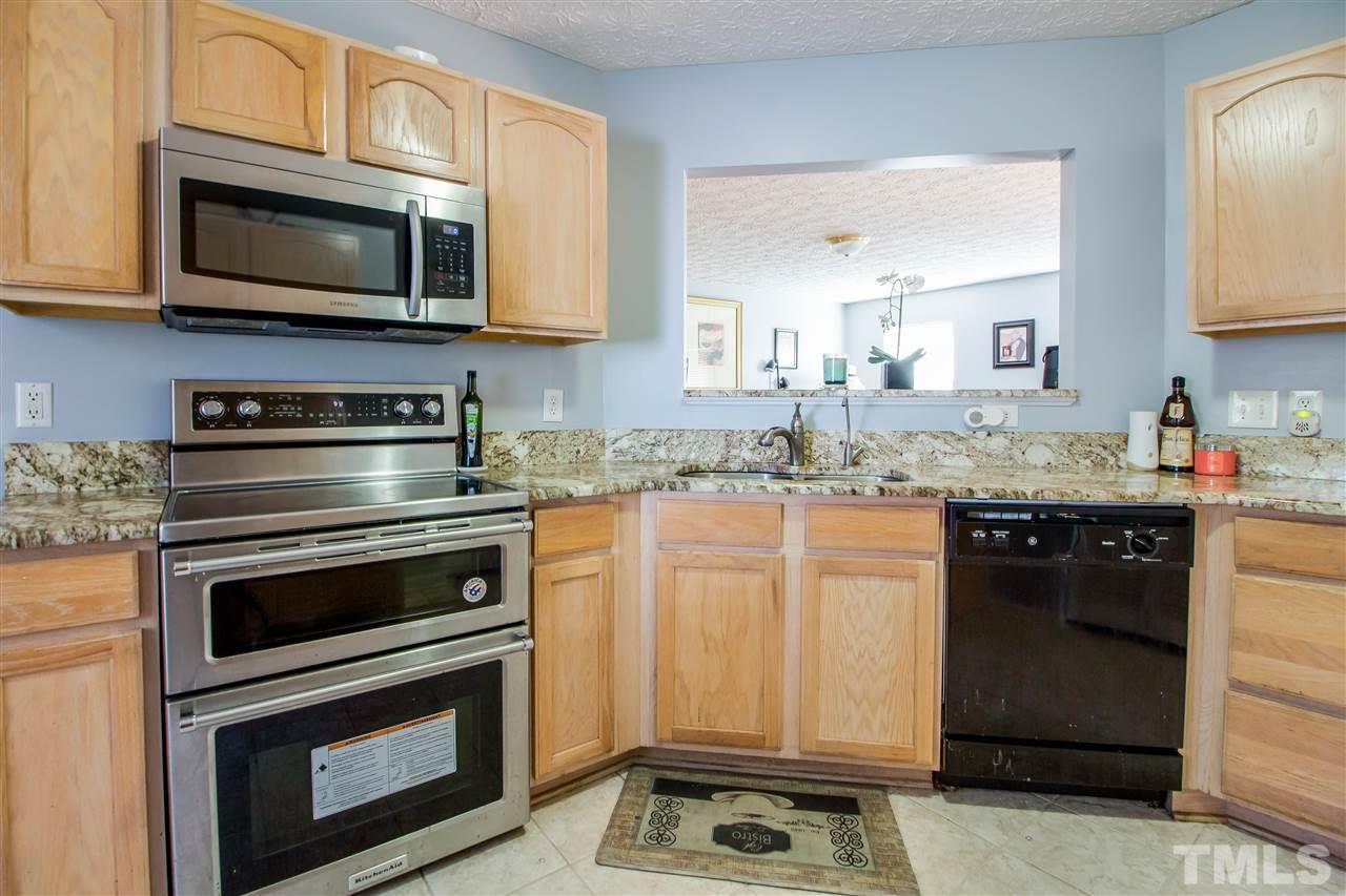 5729 Forest Point Road Raleigh, NC 27610 - Photo 9 of 26 a kitchen with granite countertop stove top oven microwave and cabinets