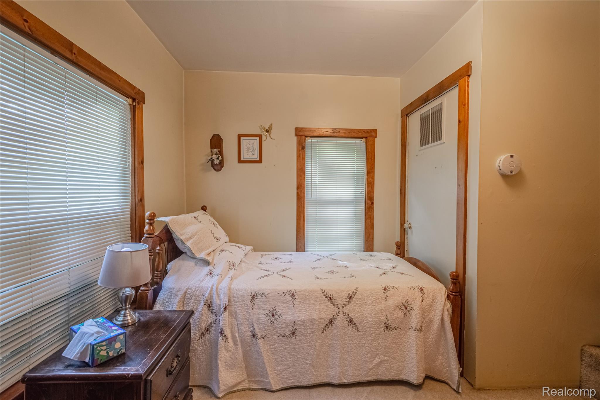 8384 Imlay City Road Avoca, MI 48006 - Photo 31 of 39 Carpeted room with a wooden bed frame, two windows with blinds, wood-finish trim, and neutral-toned walls