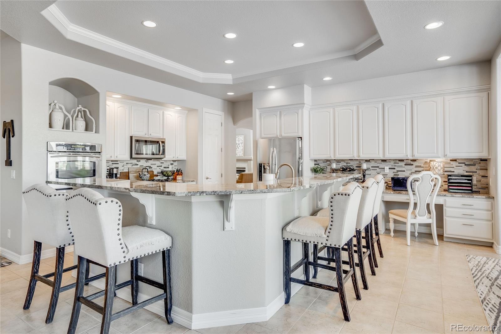 7285 Sagebrush Drive Parker, CO 80138 - Photo 17 of 46 a kitchen with stainless steel appliances kitchen island granite countertop a table and chairs
