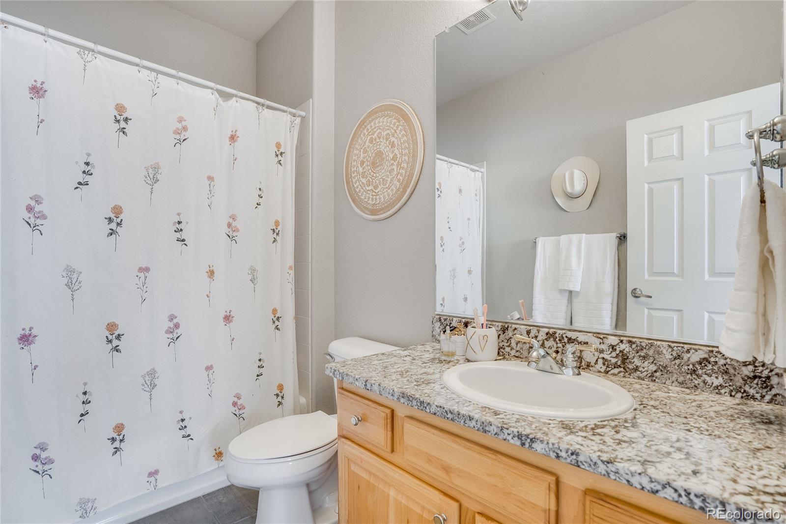 7285 Sagebrush Drive Parker, CO 80138 - Photo 28 of 46 a bathroom with a granite countertop sink a toilet and a mirror