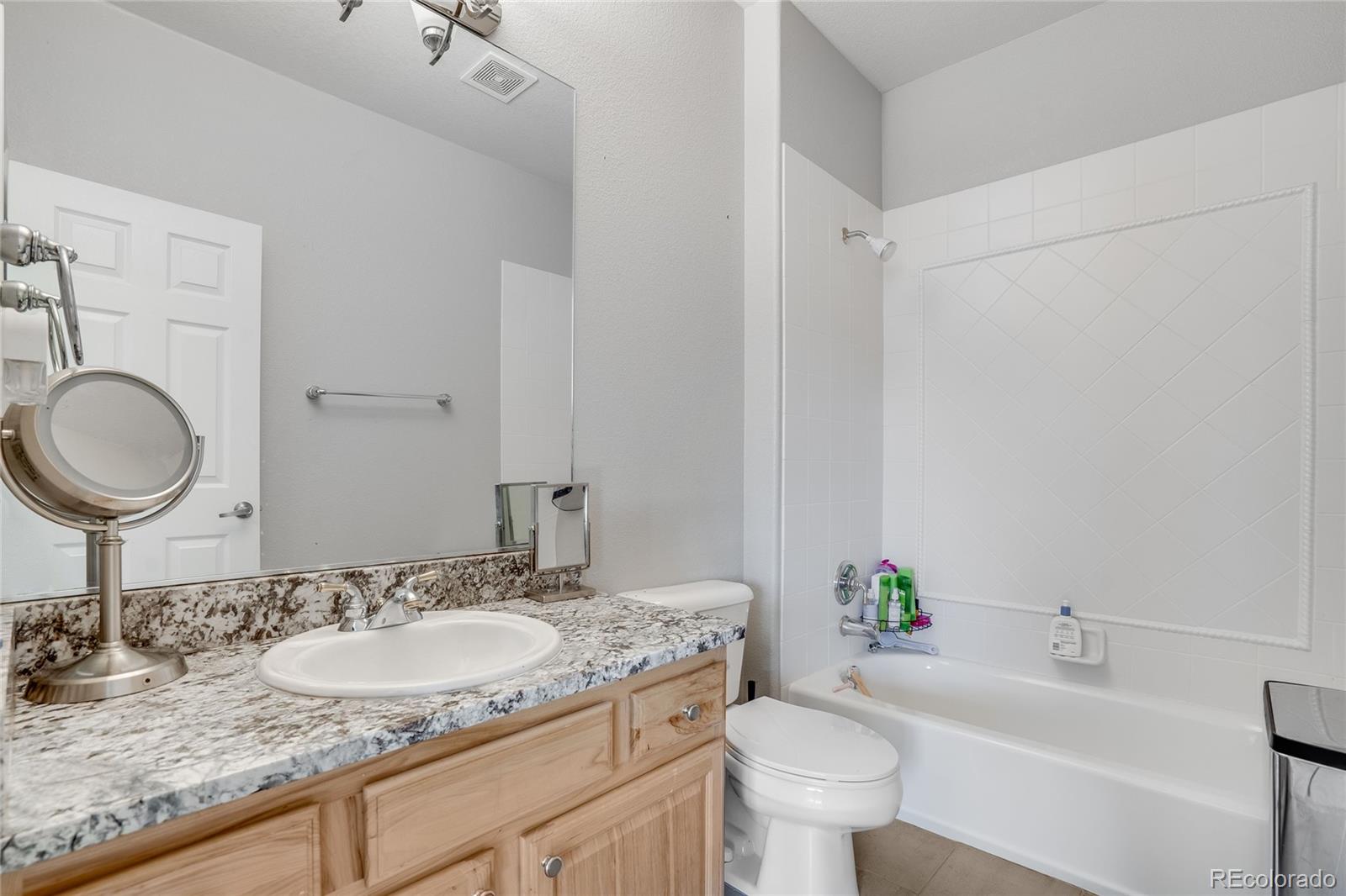 7285 Sagebrush Drive Parker, CO 80138 - Photo 32 of 46 a bathroom with a granite countertop sink toilet and a mirror