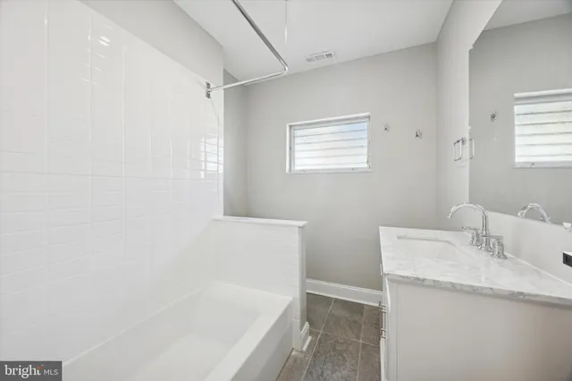a bathroom with a granite countertop sink and a bathtub