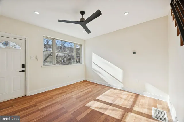 a view of empty room with wooden floor and fan