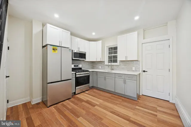 a kitchen with a refrigerator a microwave and white cabinets
